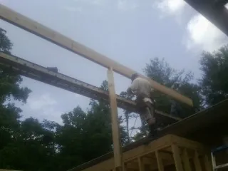 Carpenter setting a ridge beam over a new addition frame — Ice Dam Removal by Roofing Brothers in Albion